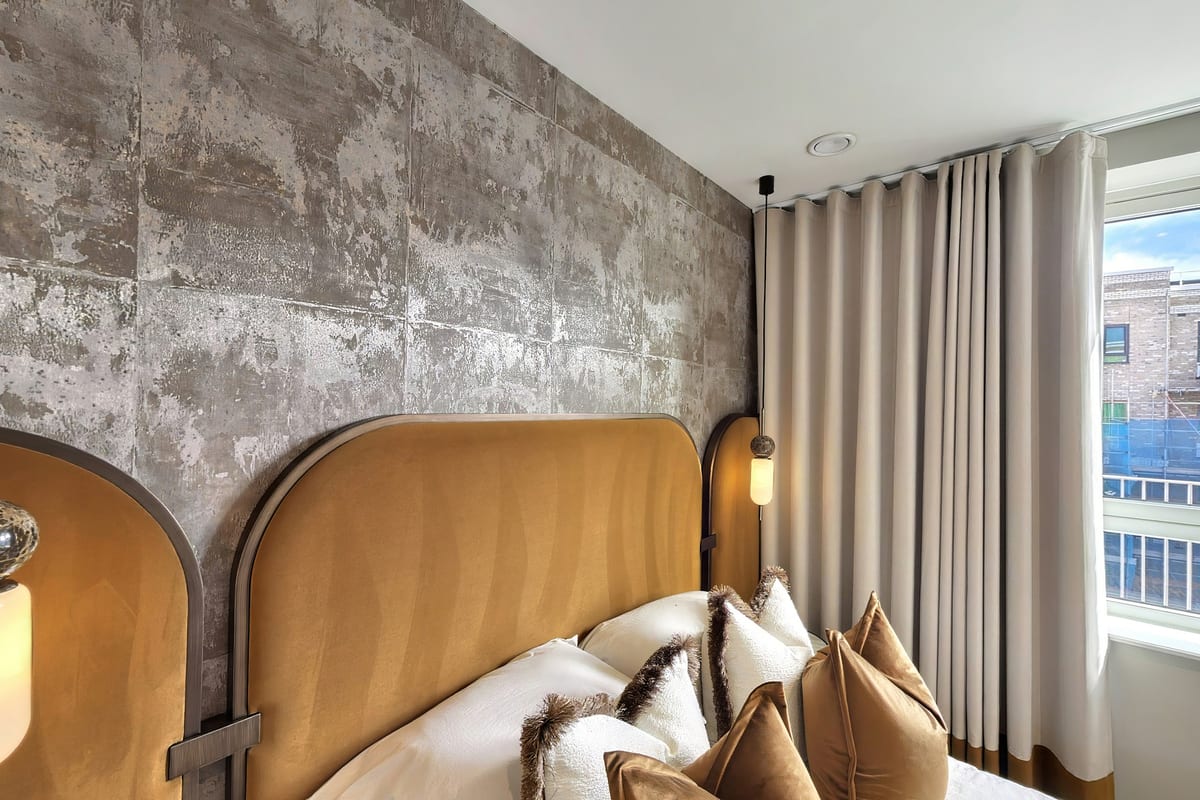 Bedroom with a curved tan leather headboard set against a textured grey feature wall