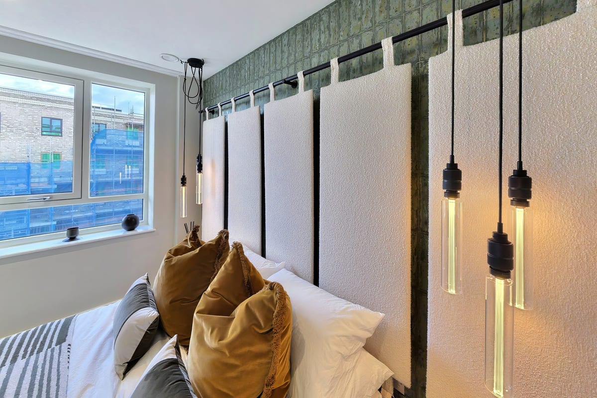 Second bedroom with a panelled headboard, green glazed tiles and glass pendant lights