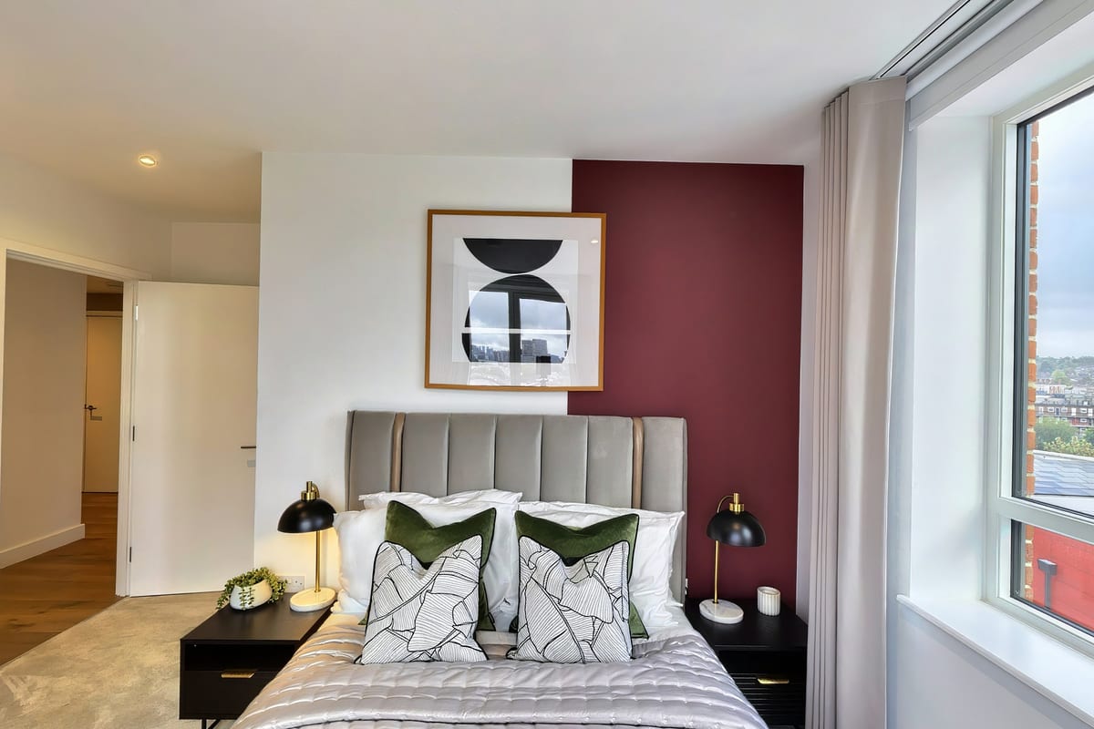 Bedroom with a burgundy feature wall, grey channel-tufted headboard and graphic artwork