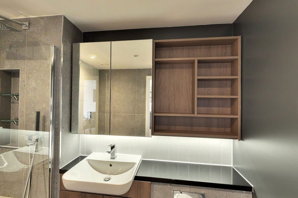 Bathroom with a walnut-framed mirrored cabinet, backlit shelf and white basin