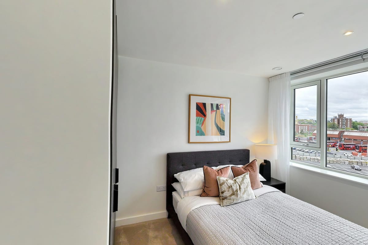 Bedroom with a charcoal headboard, blush cushions and a colourful abstract print