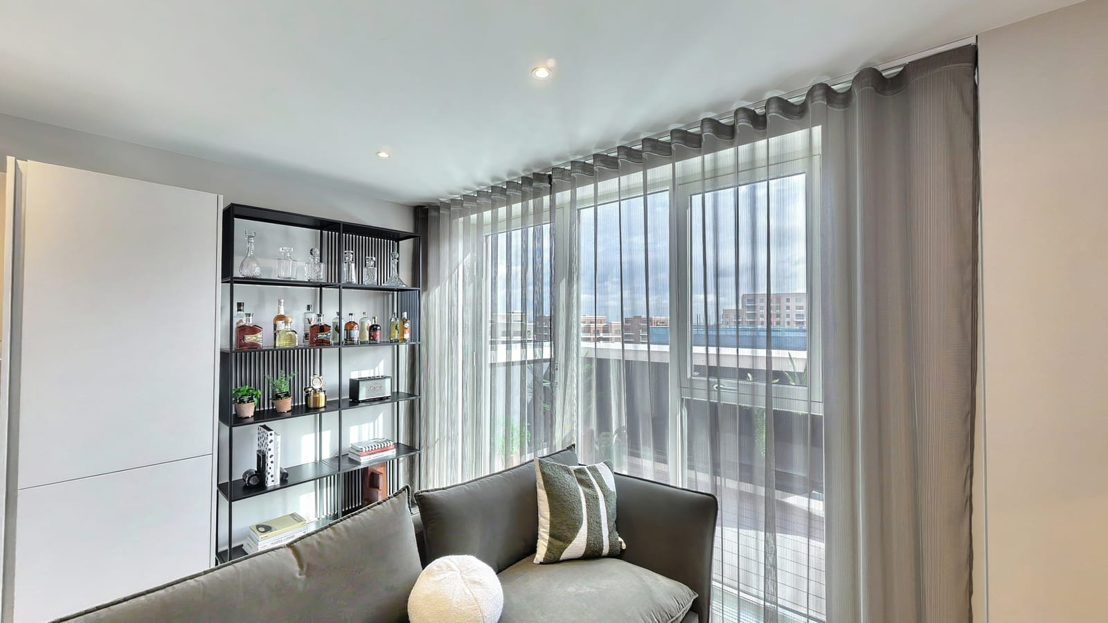 Living area in the Fero House show apartment with black drinks shelving, a charcoal sofa and full-height windows
