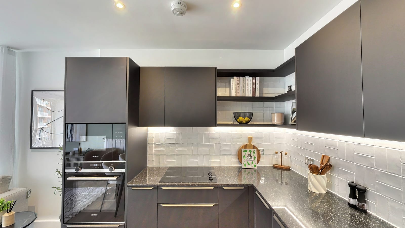 Kitchen in Myro House apartment 7.1-07-03 with charcoal cabinets, open shelving and a grey stone worktop