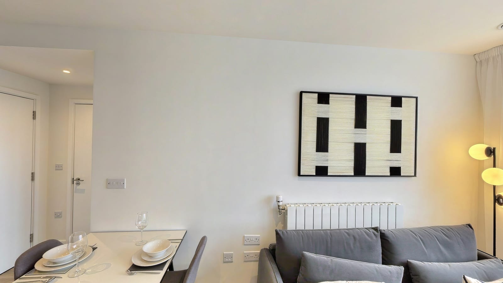 Living room in Opal House apartment 2.1-05-05 with a grey sofa below a black and white abstract canvas