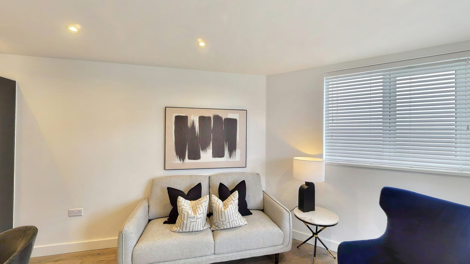 Living room in Rosa House apartment 4.1-07-10 with a cream sofa, abstract artwork and a navy armchair